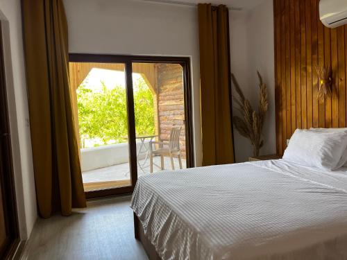 a bedroom with a bed and a door to a balcony at Sunset Boutique Hotel & Apartments in Cıralı