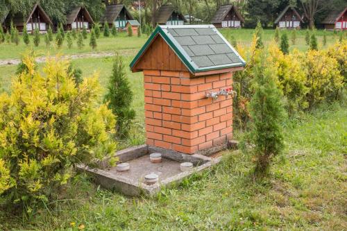 a small brick house with a roof in a field at Pensiune și Camping Patru - Gheorgheni in Gheorgheni