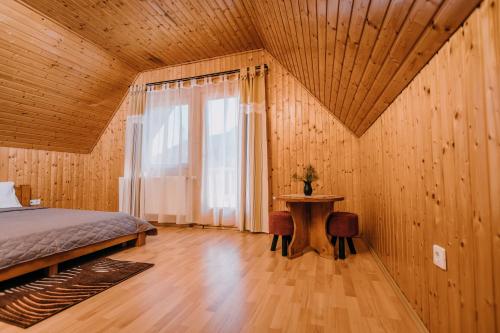 a bedroom with a bed and a table and a window at Pensiune și Camping Patru - Gheorgheni in Gheorgheni
