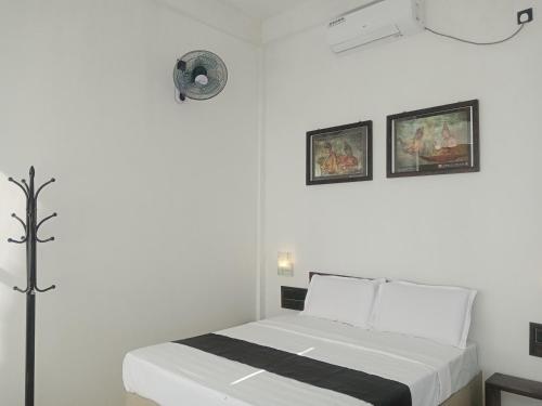 - une chambre blanche avec un lit et deux photos sur le mur dans l'établissement Ridge Boundary View, à Dambulla