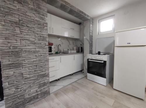 a kitchen with white cabinets and a stone wall at Apartman Amina Vinac-Jajce in Jajce