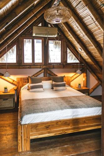 a bedroom with a large bed in a room with windows at Tiki Limbo in Montañita