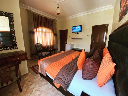 a bedroom with a bed with orange pillows and a television at Anbat Midtown Hotel in Wadi Musa