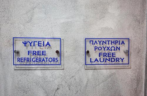 two signs on the side of a wall at RENT HOUSE ANEMOS in Iraklitsa