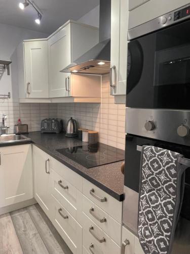 a kitchen with white cabinets and a black stove top oven at The Upper Largo Hotel & Restaurant in Lundin Links