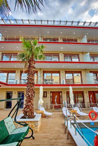 a building with a palm tree and a pool at RENT HOUSE ANEMOS in Iraklitsa