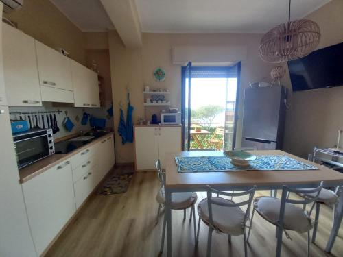 uma cozinha com uma mesa e cadeiras e uma cozinha com uma janela em IL VELIERO em Scilla