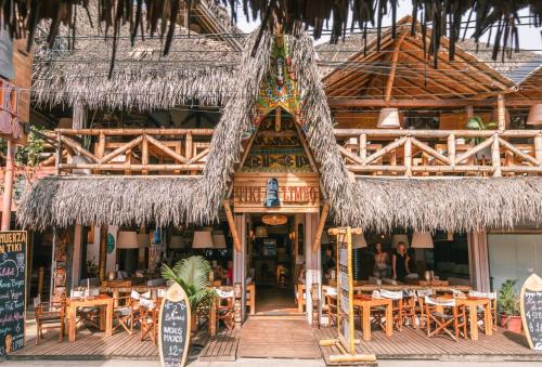 un restaurante con techo de paja, mesas y sillas en Tiki Limbo, en Montañita