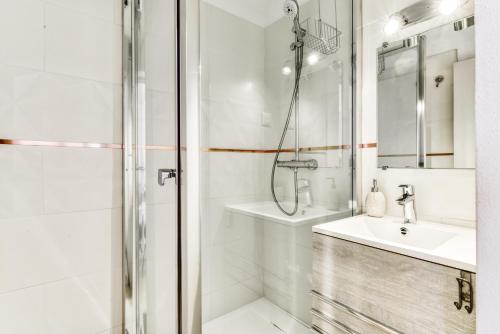een witte badkamer met een douche en een wastafel bij Méditerranée Port Soleil in Gruissan