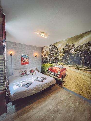 une chambre avec un lit et une peinture d'une voiture rouge dans l'établissement Bel'air Gare By Carl-Emilie 2 personnes, à Épinal