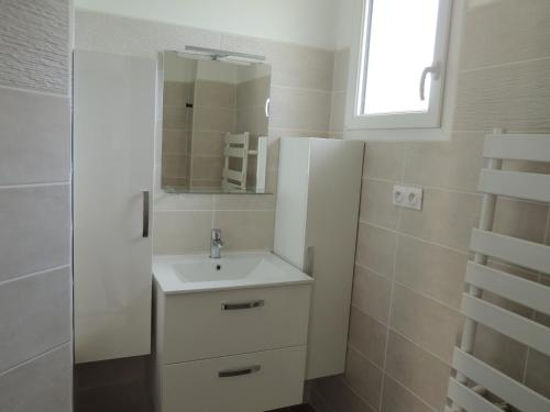 een badkamer met een witte wastafel en een spiegel bij Gîte entre terre et baie in Pontorson