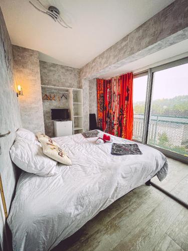 une chambre avec un lit et une grande fenêtre dans l'établissement Tassigny Gare By Carl-Emilie, à Épinal