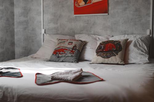 a white bed with pillows and a hat on it at Tassigny Gare By Carl-Emilie in Épinal