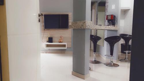 sala de estar con taburetes negros y TV en Apartamento Guarapuvu, en Florianópolis
