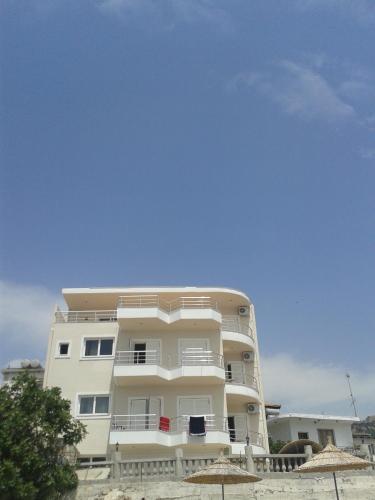 a tall white building with a blue sky in the background at Magic Ionian Apartments & Rooms in Himare