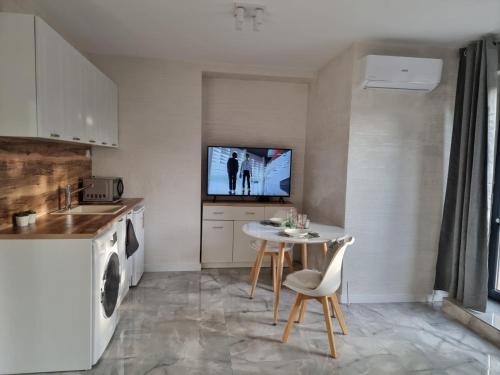 a kitchen with a table and a tv on the wall at СТУДИО АВА in Sliven