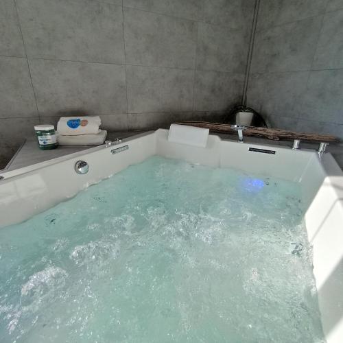 a bath tub filled with water in a bathroom at Hôtel de charme & SPA Le Grand Large in La Bernerie-en-Retz