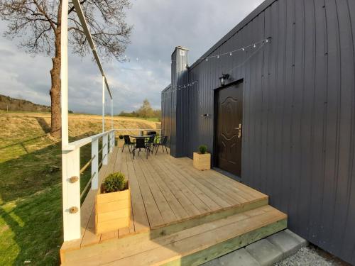 een zwart huis met een houten terras met een tafel bij Bieszczadzkie Pola in Wańkowa