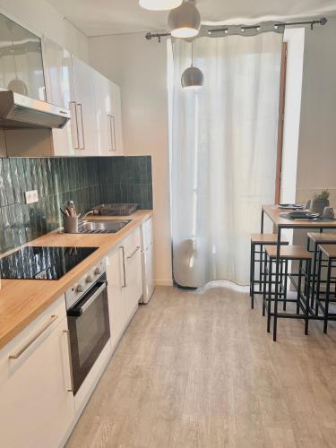 uma cozinha com armários brancos, mesas e cadeiras em Studio Cosy en Plein Centre em Corbeil-Essonnes