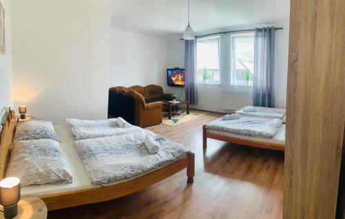 a bedroom with two beds and a chair and a window at Penzión Music in Nižný Slavkov