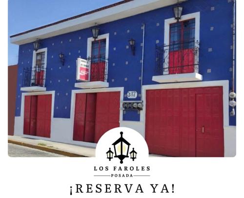 a blue building with red garage doors with the words los franciscosos rooms at Hotel Posada Los Faroles Atlixco in Atlixco