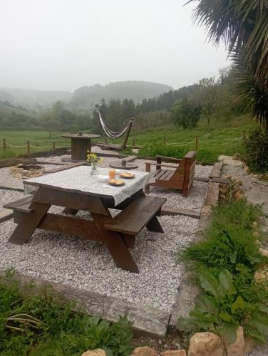 a picnic table and bench in a garden at Glamping Quintana in Gijón