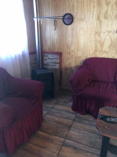 a living room with two chairs and a stove at Cabañas melinka in Licán Ray