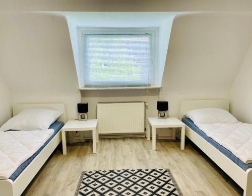 2 Betten in einem Zimmer mit 2 Tischen und einem Fenster in der Unterkunft FeWo with six Beds an six Guests in Hagen