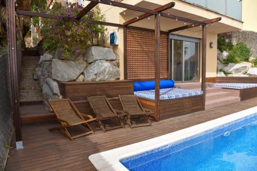 a deck with chairs and a bed next to a swimming pool at Villa Miramar Panoramic Views in Santa Susanna