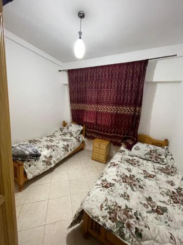 a bedroom with two beds and a curtain at Appartement Familial Al Hoceima WiFi in Al Hoceïma