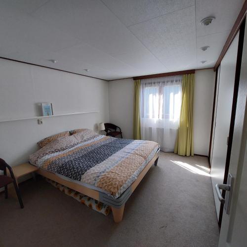 a bedroom with a bed and a window with yellow curtains at Vakantie op de Veluwe in Lunteren