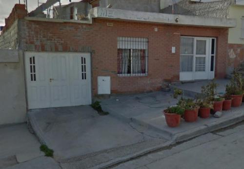 ein Gebäude mit einer weißen Garage mit Topfpflanzen in der Unterkunft Lo de Juana in Trelew