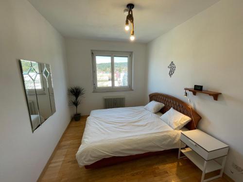 a bedroom with a bed with white sheets and a window at Spacious 3bd top floor flat close to lake (103m²) in Klagenfurt
