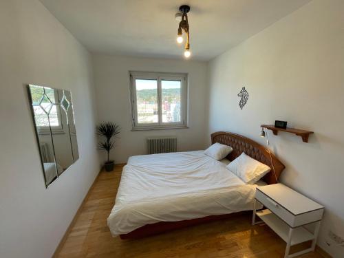 ein Schlafzimmer mit einem Bett mit weißen Laken und einem Fenster in der Unterkunft Spacious 3bd top floor flat close to lake (103m²) in Klagenfurt am Wörthersee