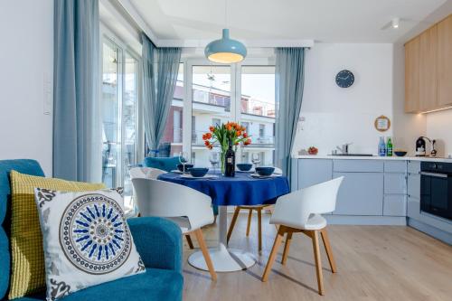Il dispose d'une cuisine et d'un salon avec une table et des chaises bleues. dans l'établissement Apartament z basenem "Przy Morzu", à Rewal
