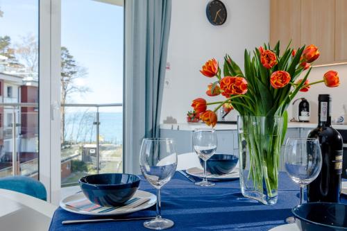 une table avec un vase de fleurs et des verres à vin dans l'établissement Apartament z basenem "Przy Morzu", à Rewal