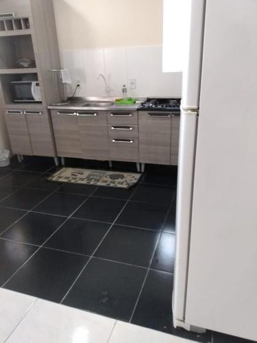 a kitchen with a white refrigerator and a black tile floor at Casa na Praia de Ingleses in Florianópolis