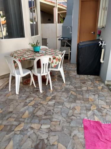 a patio with a table and chairs on a stone floor at Casa na Praia de Ingleses in Florianópolis