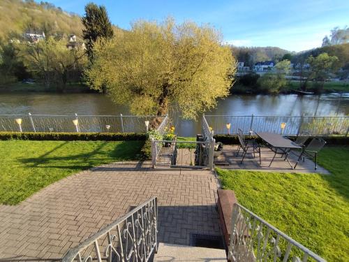 a patio with a table and a tree next to a river at Doppelzimmer an der Lahn ohne Küche in Obernhof