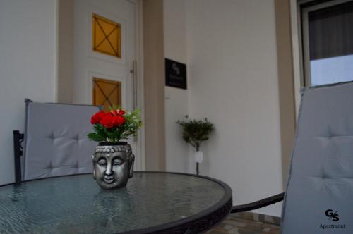 G.S. Apartment في ماستيخاري: طاولة مع مزهرية مع الزهور الحمراء عليها