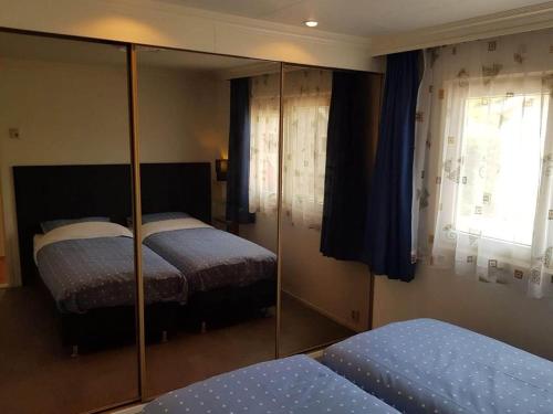 een slaapkamer met 2 bedden en een spiegelkast bij Inviting bungalow in Gelderland with garden in Garderen