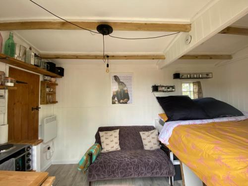 a small bedroom with a bed and a chair at Mr Hares shepherd hut in Mellis