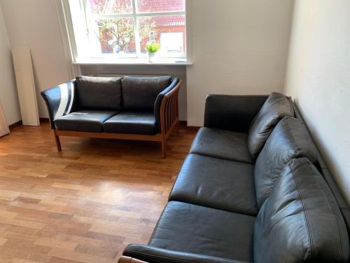 a living room with a leather couch and a chair at Idrætscenter Jammerbugt in Fjerritslev