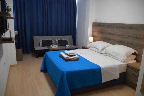 a bedroom with a bed with a blue blanket and a chair at Sea Krystel 603 in Larnaca