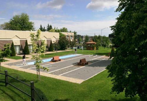 a park with a pool and benches and a building at Hotel L'Oiseliere Montmagny in Montmagny