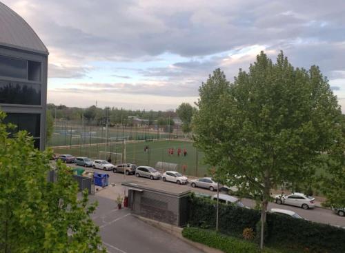 a parking lot with cars parked next to a field at Loft Confort in Alcalá de Henares