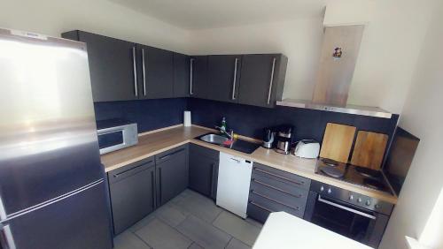 a small kitchen with black cabinets and white appliances at Pension beim Kastell in Sulz am Neckar