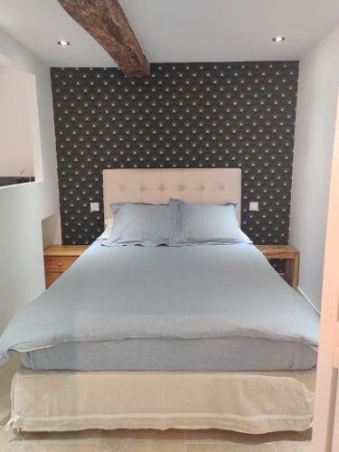 - une chambre avec un grand lit et un mur à motifs dans l'établissement Logement neuf centre du village aux pieds du château, à Grimaud