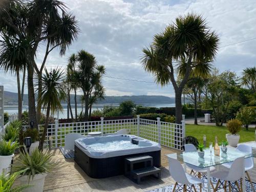 bañera de hidromasaje en una terraza con mesa y sillas en Seaview Cottage on the Island, 