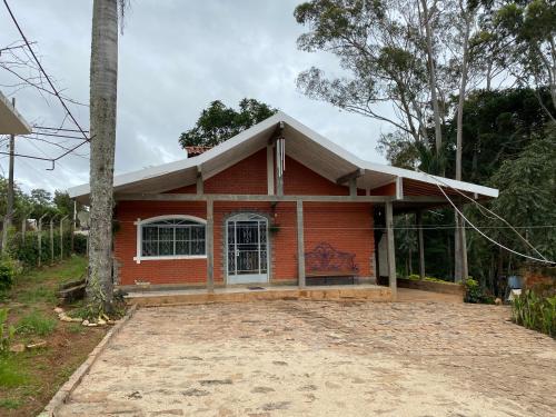 a red house with a tree in front of it at Pousada La na Roça in Paraisópolis